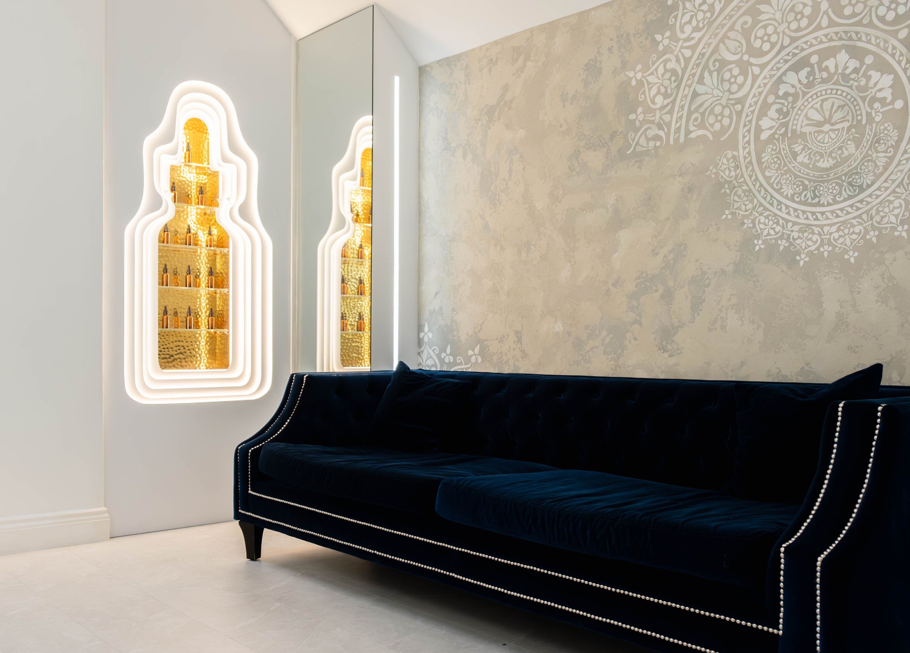Elegant waiting area at Dr Kajal Aesthetics, London, England, GB with plush sofa and ornate wall design.
