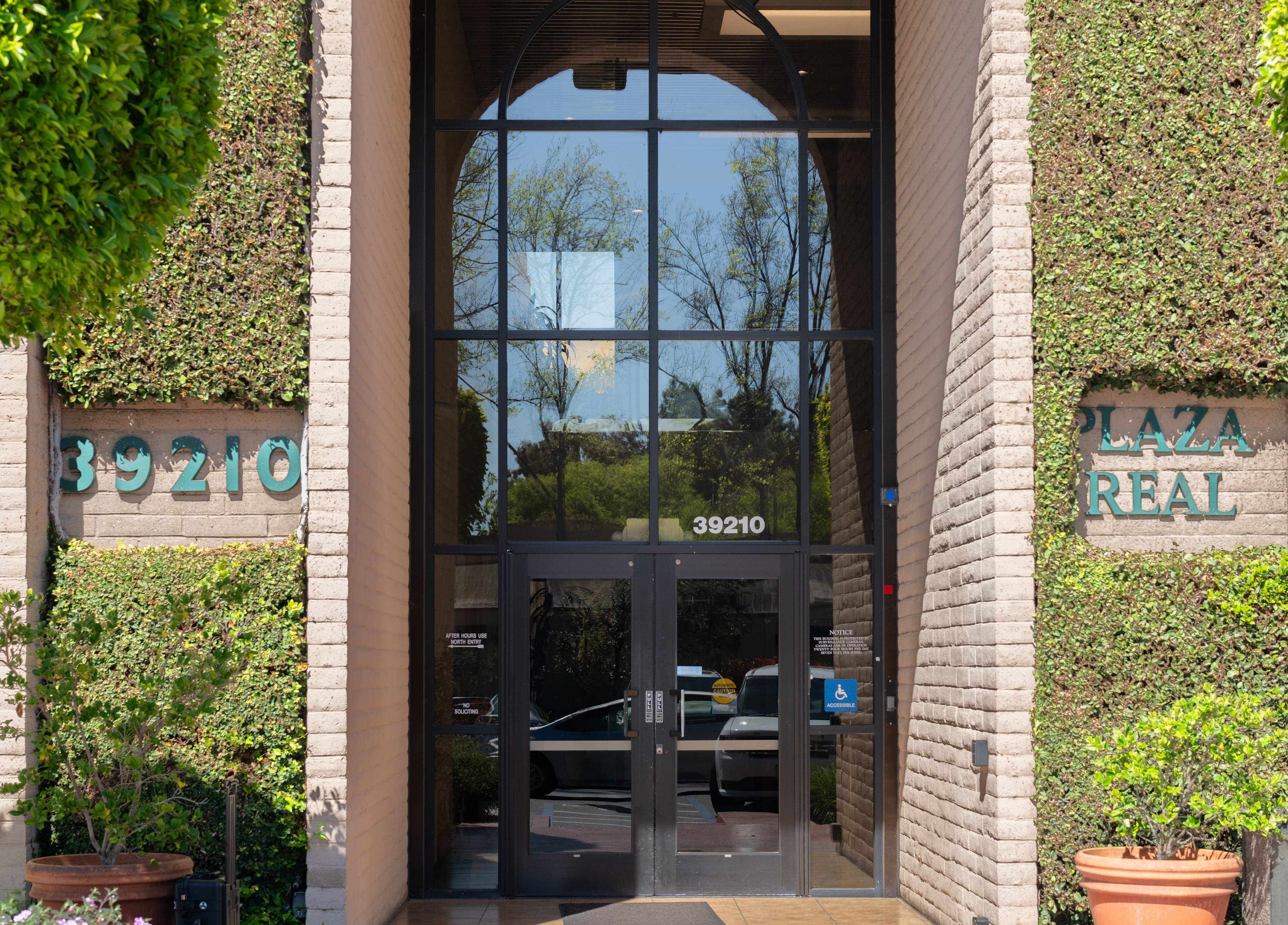 Entrance of Ibeauty PMU and Lashes at 39210 Plaza Real, Fremont, California, US with ivy-covered walls.