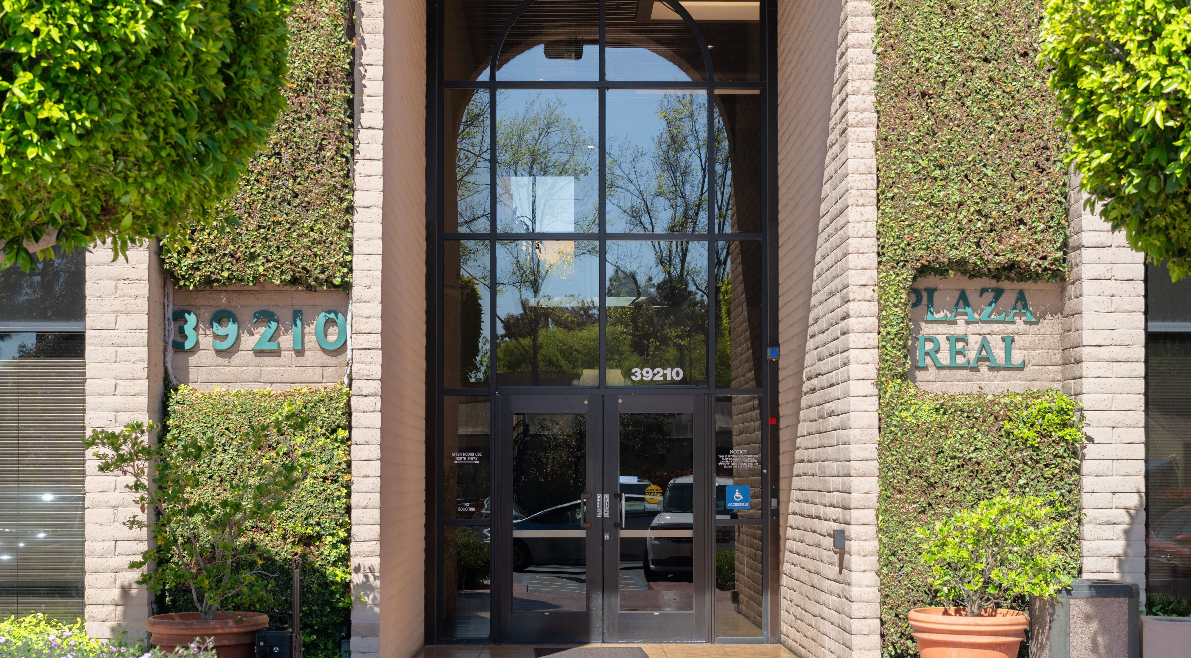 Entrance of Ibeauty PMU and Lashes at 39210 Plaza Real, Fremont, California, US with ivy-covered walls.