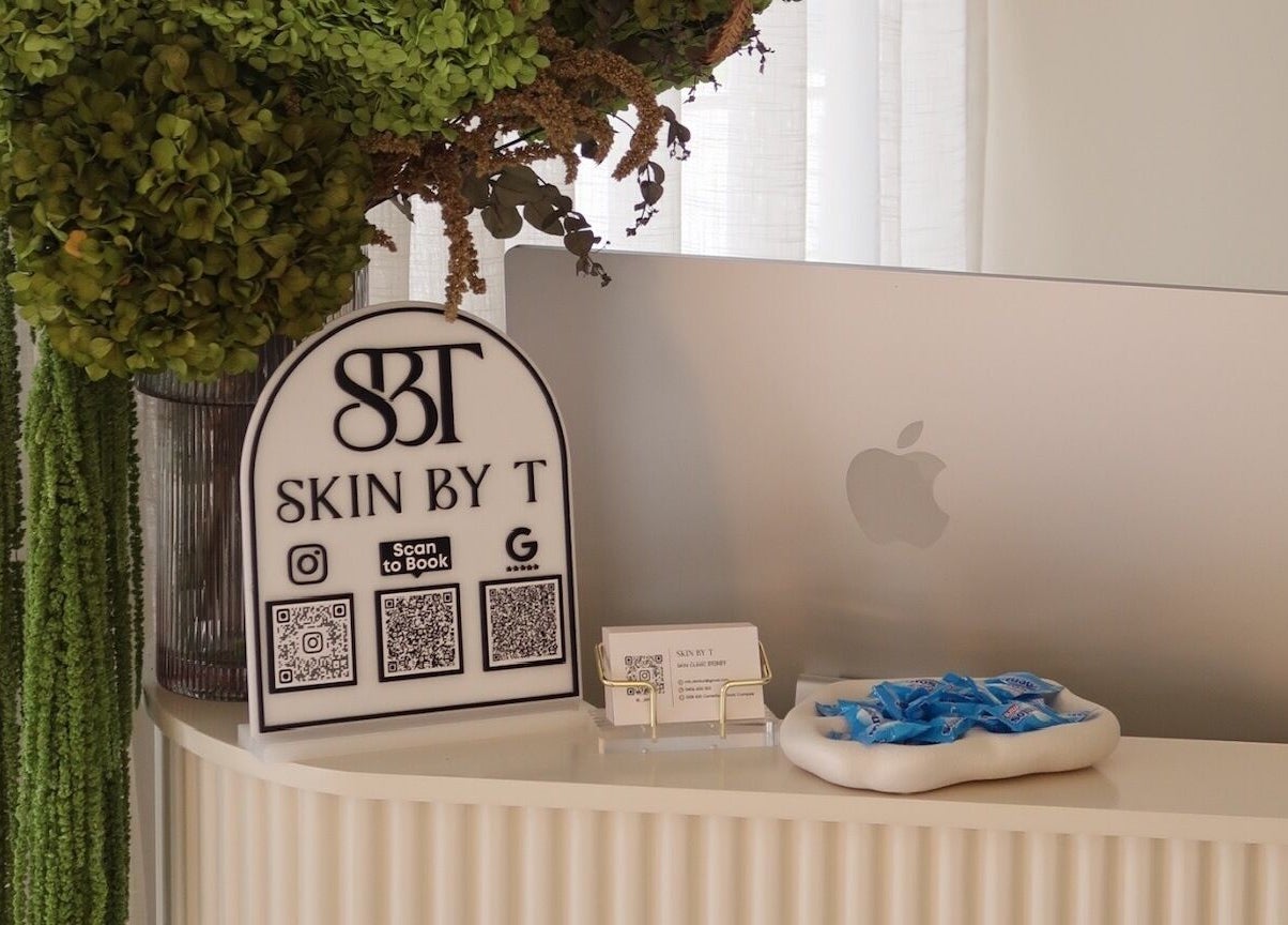 Skin By T reception desk in Campsie, New South Wales, AU, featuring a computer and decorative greenery.