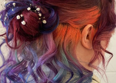 Brightly colored hairstyle at Lissybeth Hair @ Hybrid, Truro, England, GB, showcasing vibrant curls and delicate flowers.