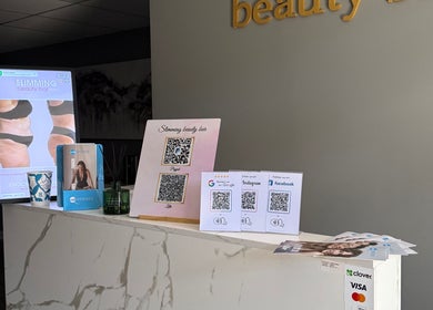 Reception area at Slimming Beauty Bar, Aurora, Illinois, showcasing displays and QR codes for social media.