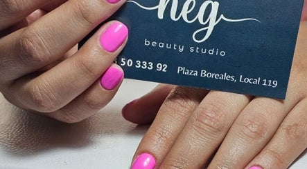Manos con uñas rosas sosteniendo tarjeta de NEG Beauty Studio en Zapopan, Jalisco, MX.
