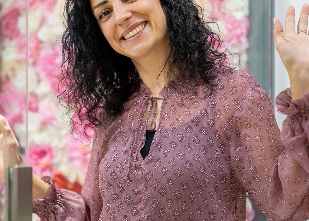 Person smiling warmly at Geri Nails Art Studio, London, England, GB with floral backdrop.