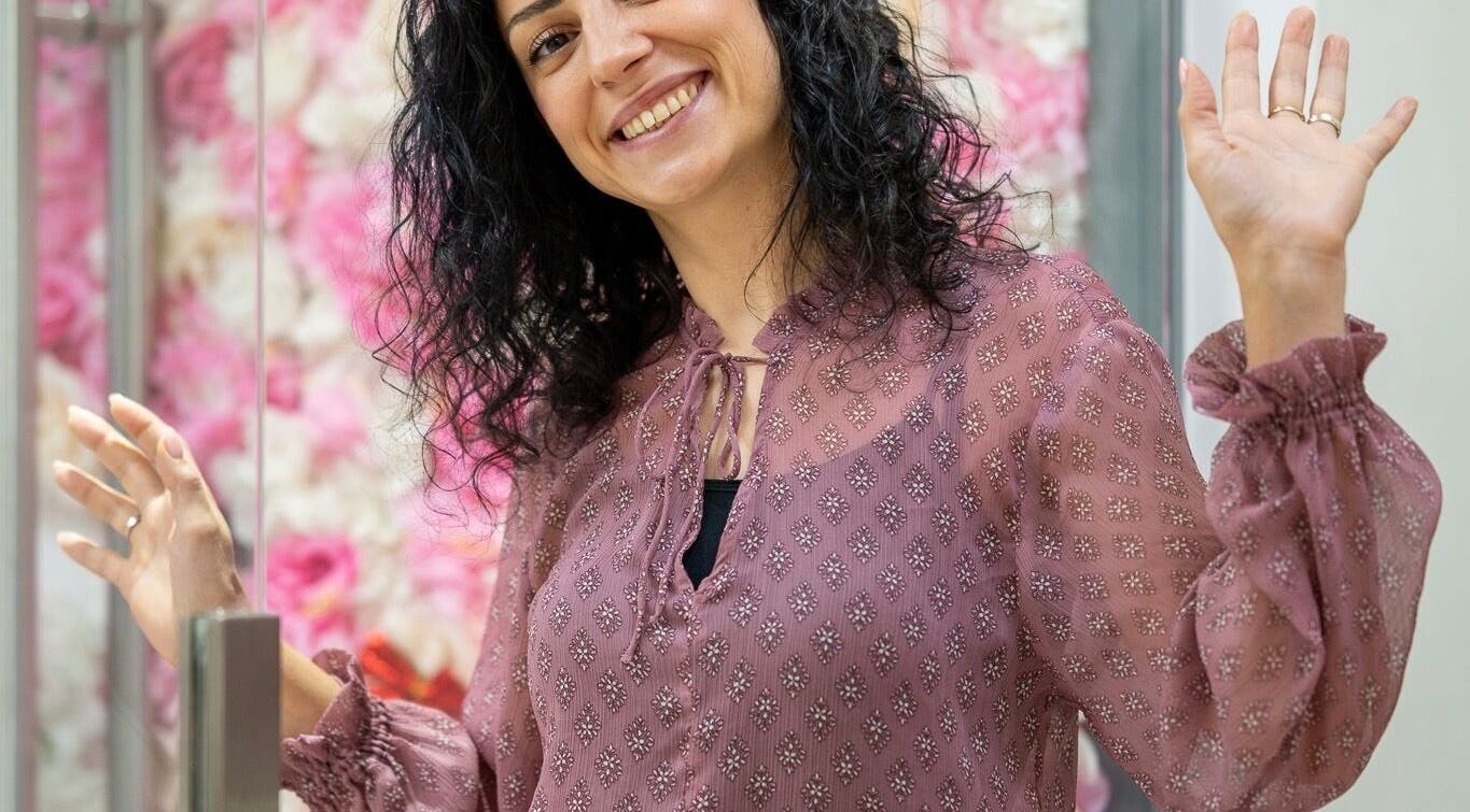 Person smiling warmly at Geri Nails Art Studio, London, England, GB with floral backdrop.