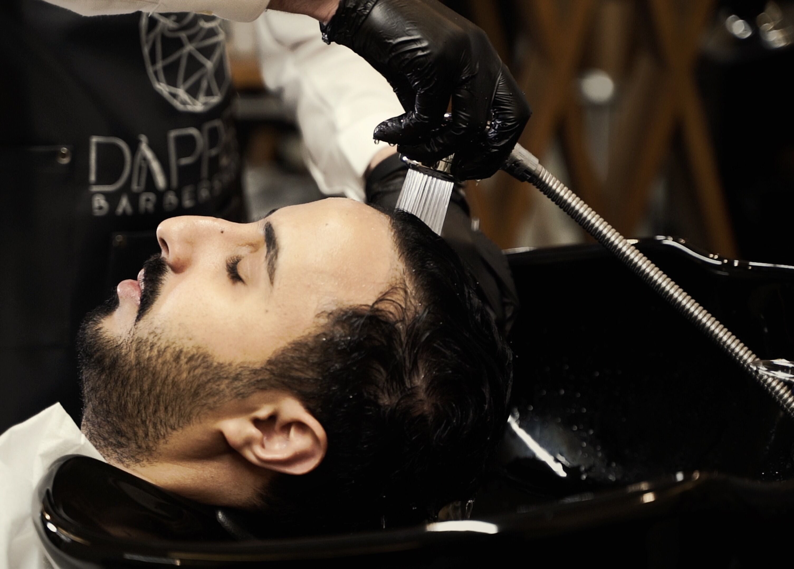 Client enjoys a soothing hair wash at Dapper Barbershop in Dhahran, Eastern Province, SA.