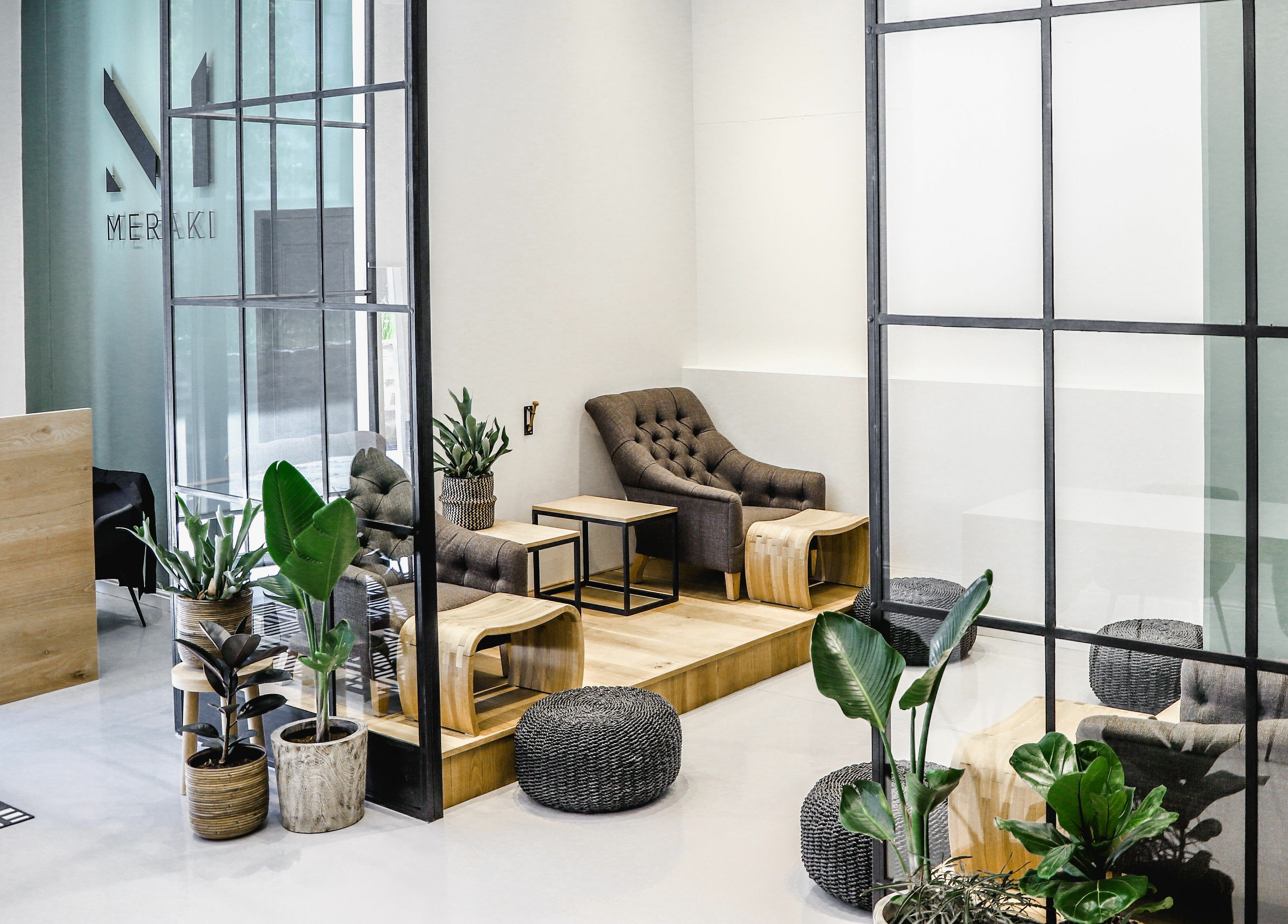 Elegant lounge area at Meraki Aesthetics, Cape Town, Western Cape, ZA with modern decor and lush plants.