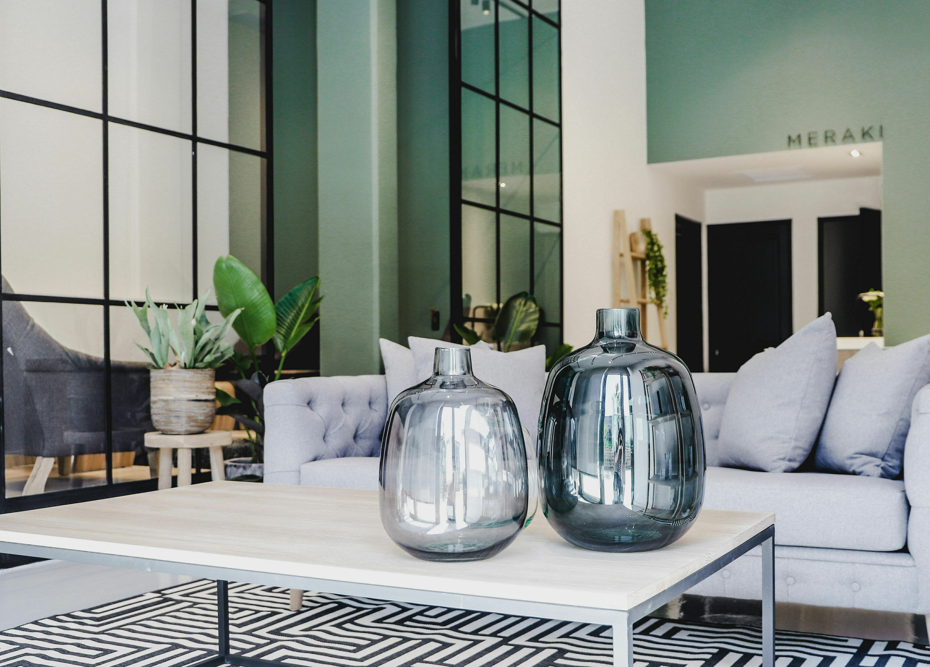 Elegant seating area at Meraki Aesthetics, Cape Town, Western Cape, ZA featuring glass vases and lush plants.