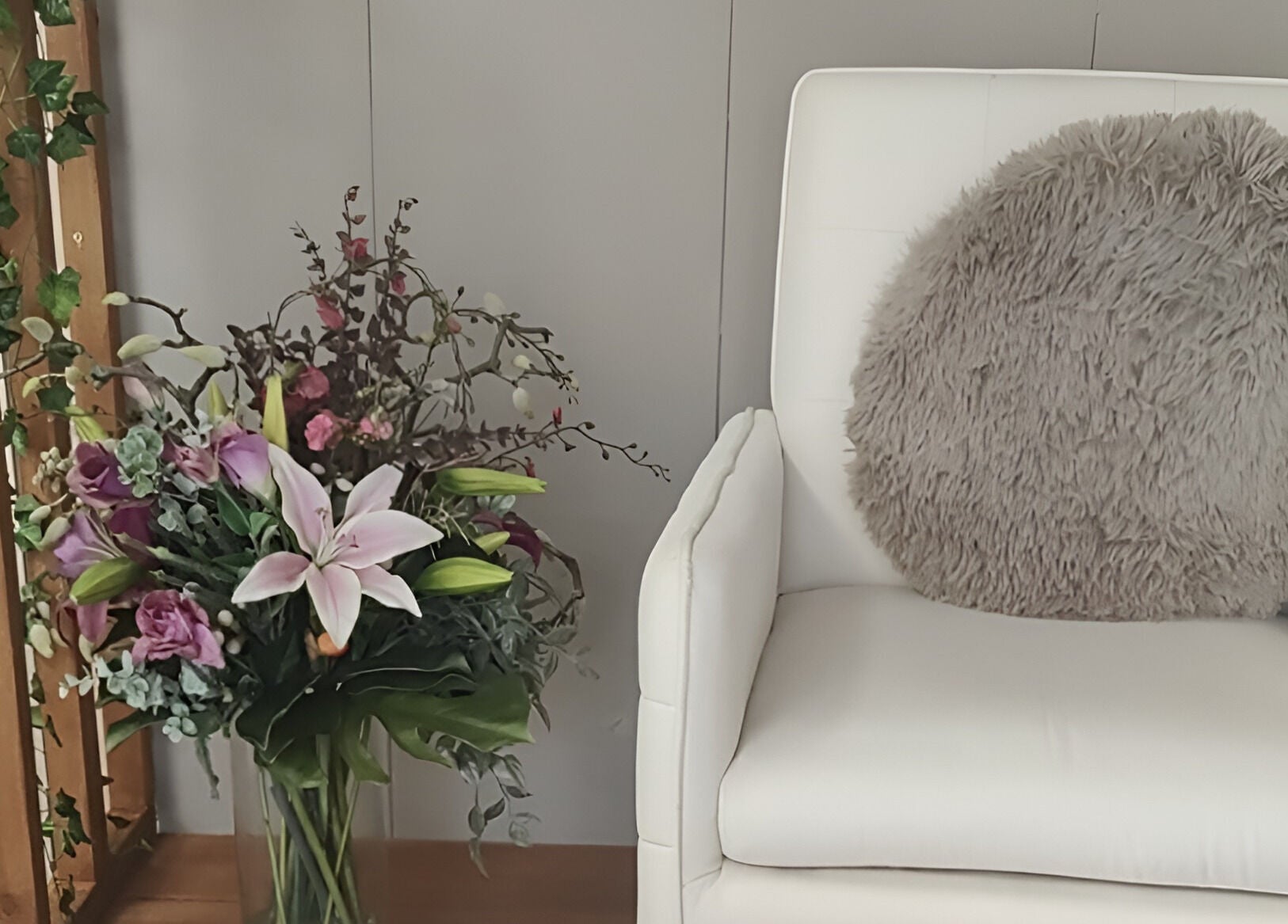 Cozy corner at Oh La Lash and Beauty, Llanelli, Wales, GB with chic white chair and vibrant floral display.