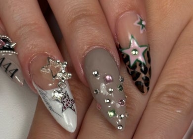 Manicura artística en Nails by Caprii, Avilés, ES, con gemas brillantes y diseño estelar único.
