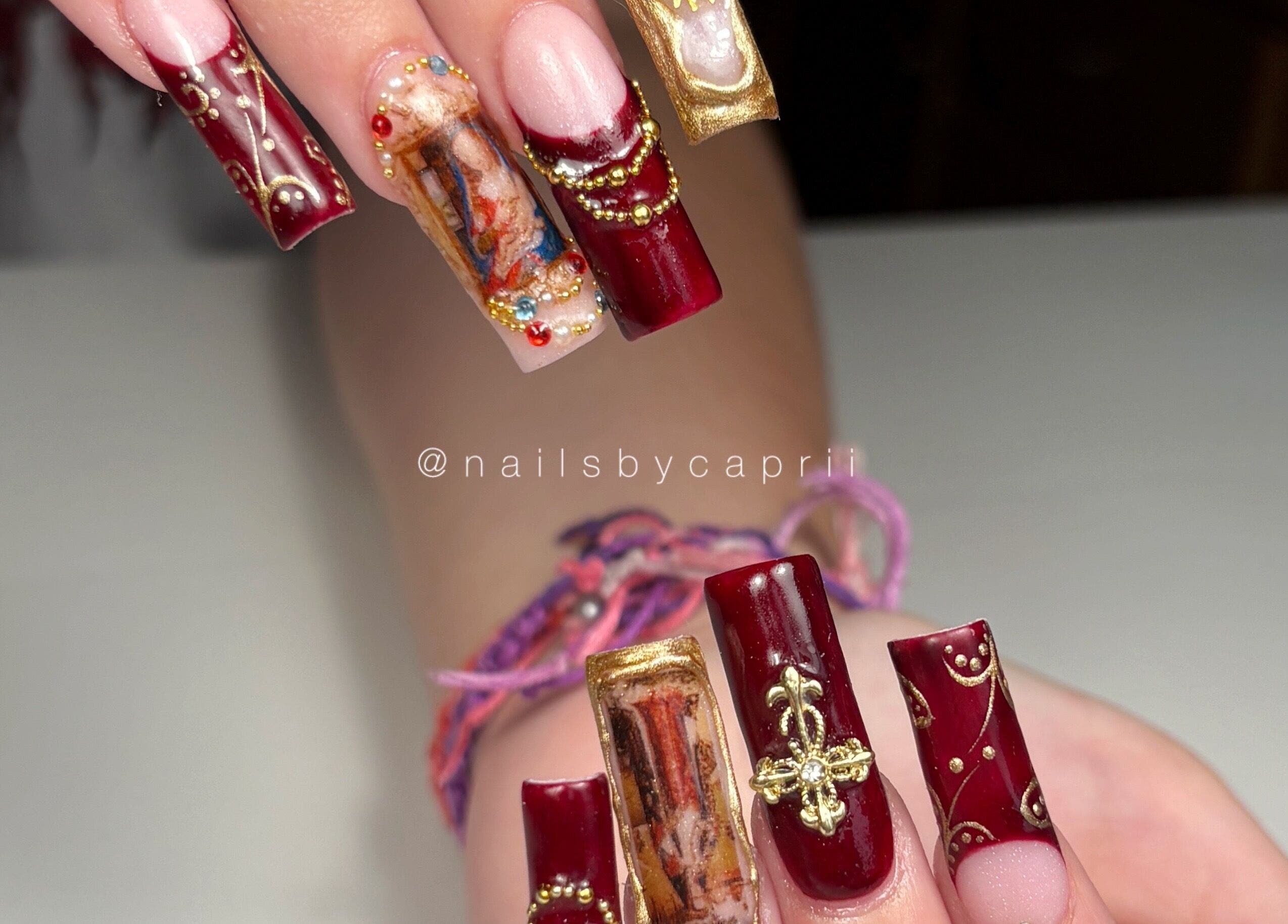 Arte en uñas rojas con detalles dorados de Nailsbycaprii en Avilés, ES.