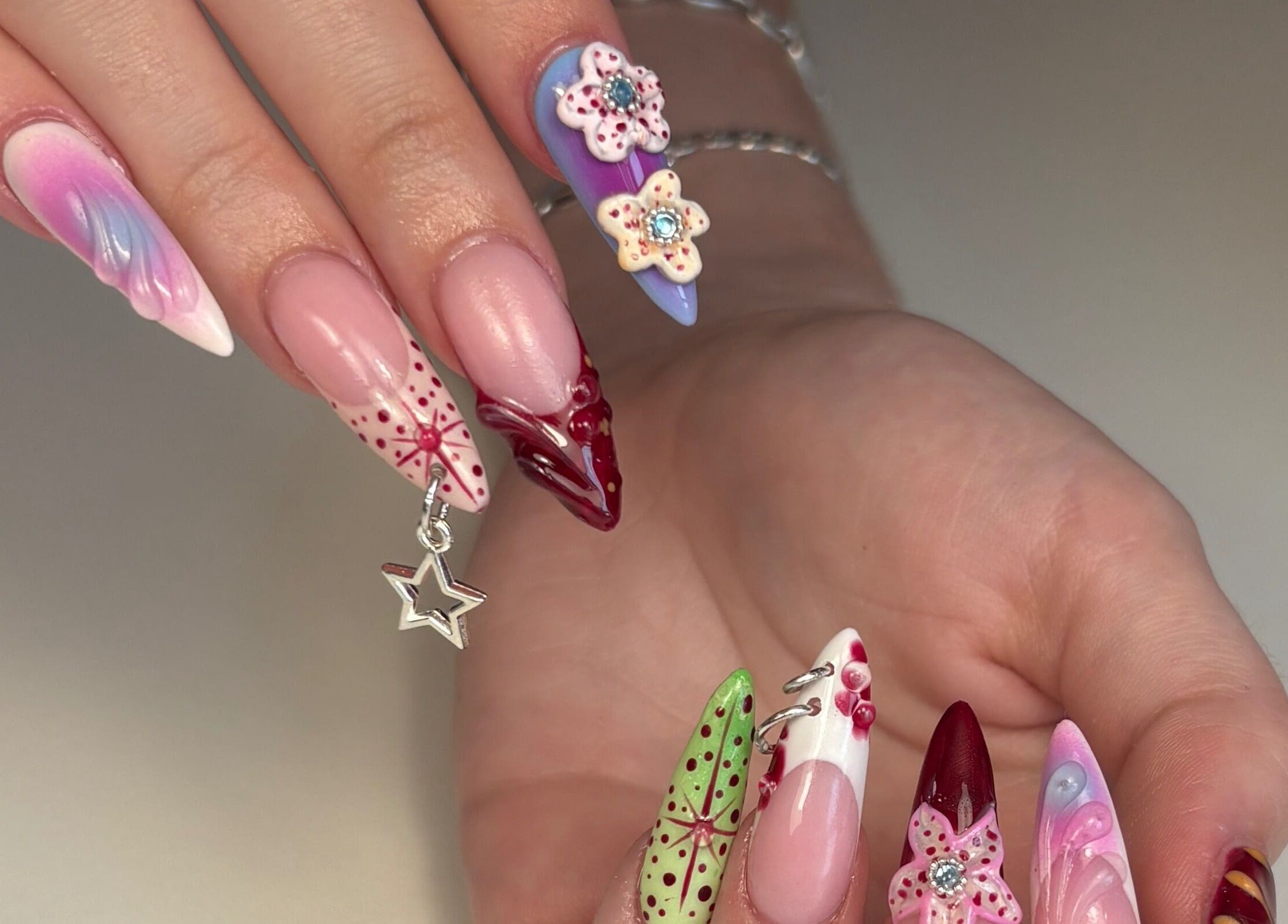 Diseños únicos de uñas en Nailsbycaprii, Avilés, ES, con arte floral y efectos multicolores.