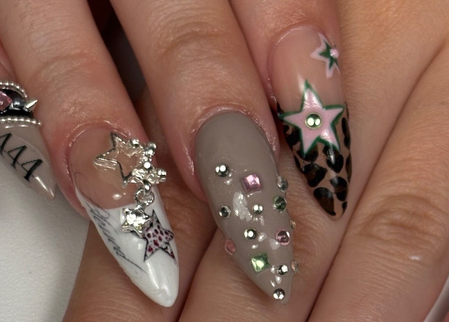 Diseño creativo de uñas en Nailsbycaprii, Avilés, ES, con joyas y estrellas brillantes.