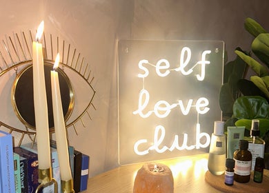 Serenity Seven, Hamilton Scotland, GB: glowing candles beside 'self love club' sign and wellness items.