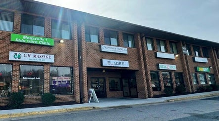 Front view of CH Massage in Woodbridge, Virginia, US, at a brick plaza, alongside neighboring businesses.