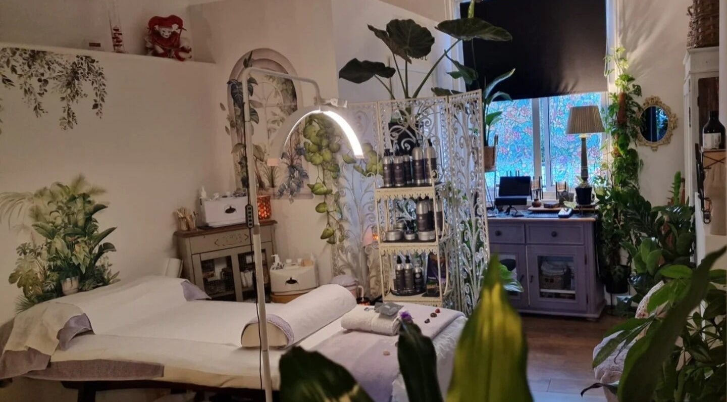 Calming wellness space at Tranquility in Hastings, England, GB, features lush plants and cozy massage bed.