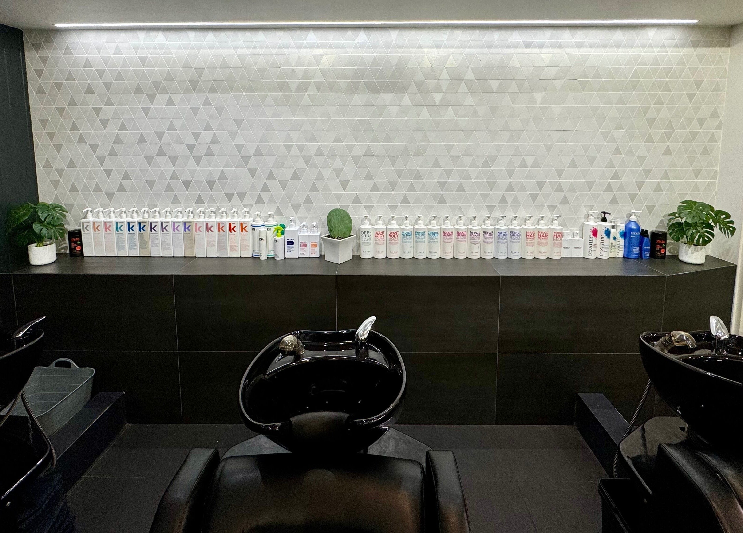 BAE Salon's modern shampoo area in Woolooware, New South Wales, AU featuring sleek black basins and products.