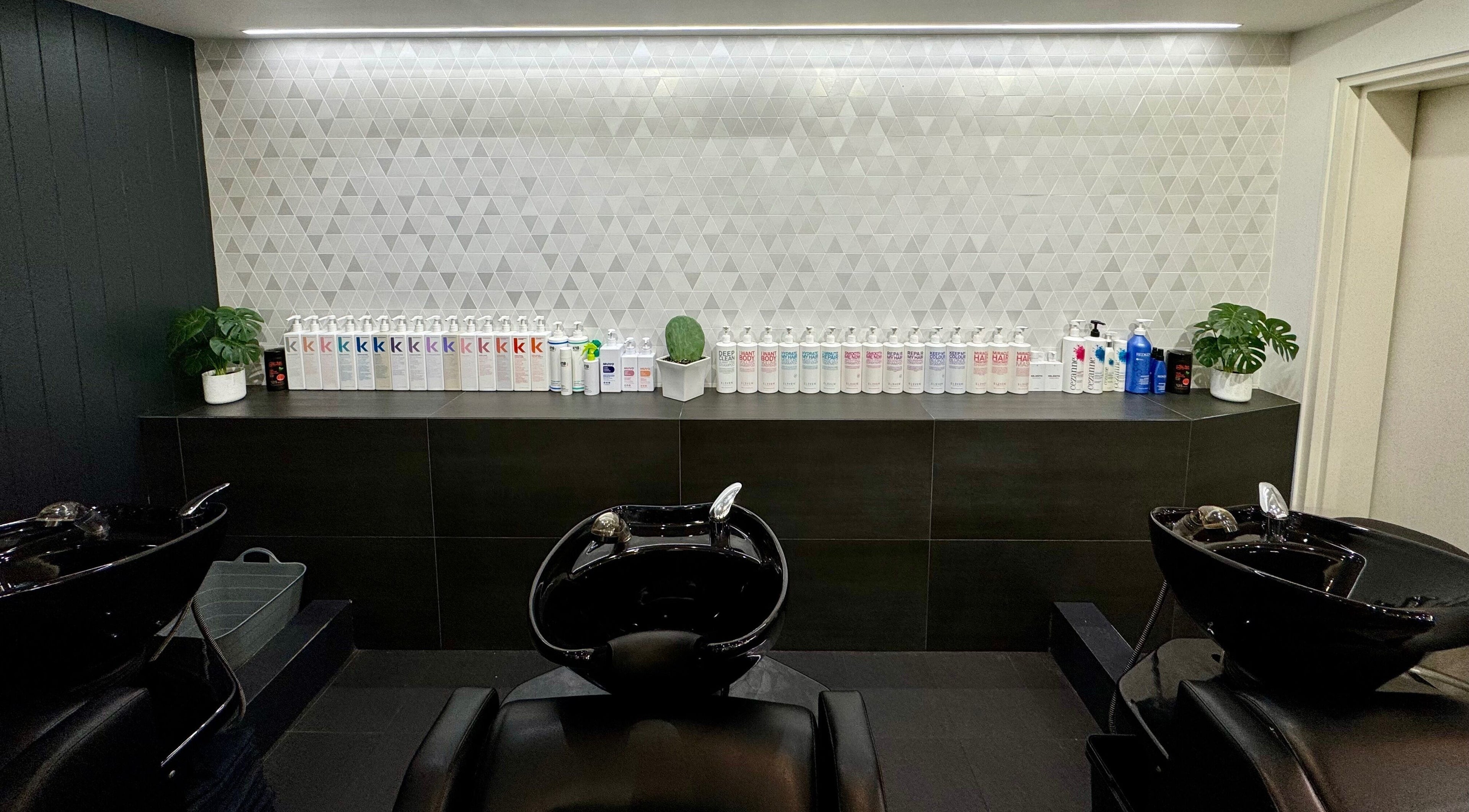 BAE Salon's modern shampoo area in Woolooware, New South Wales, AU featuring sleek black basins and products.
