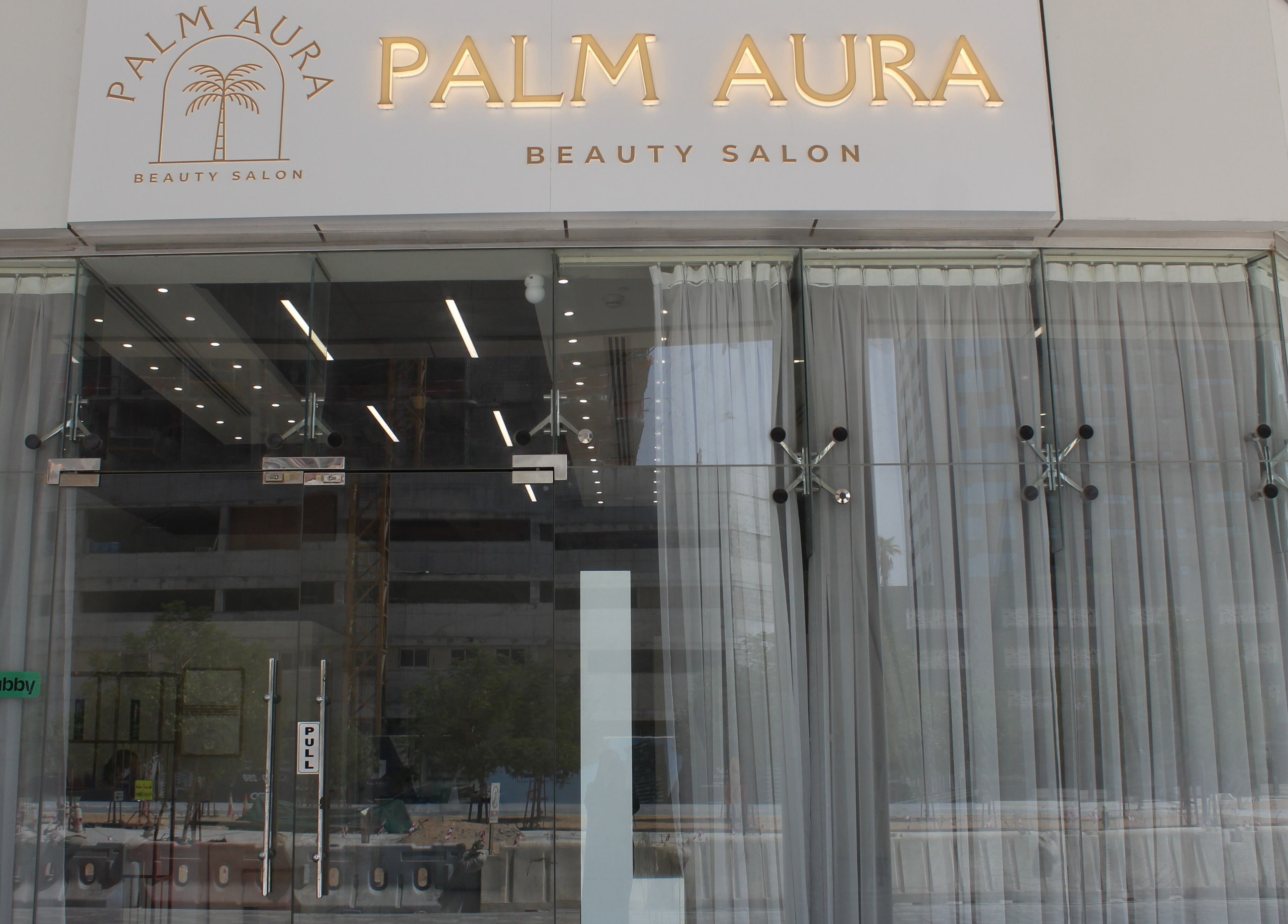Front entrance of Palm Aura Beauty Salon in Dubai, Dubai, AE, showcasing modern glass doors and signage.