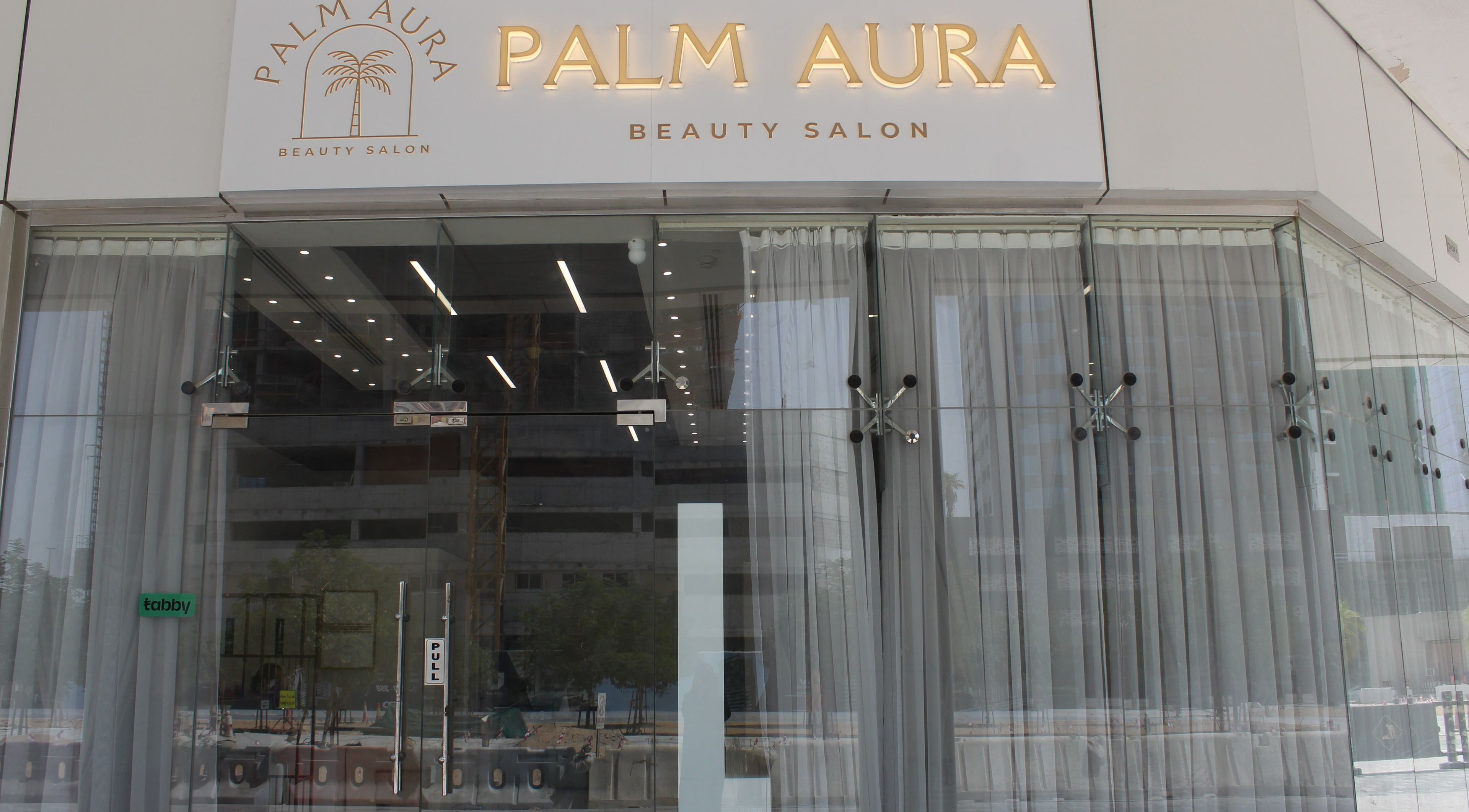 Front entrance of Palm Aura Beauty Salon in Dubai, Dubai, AE, showcasing modern glass doors and signage.