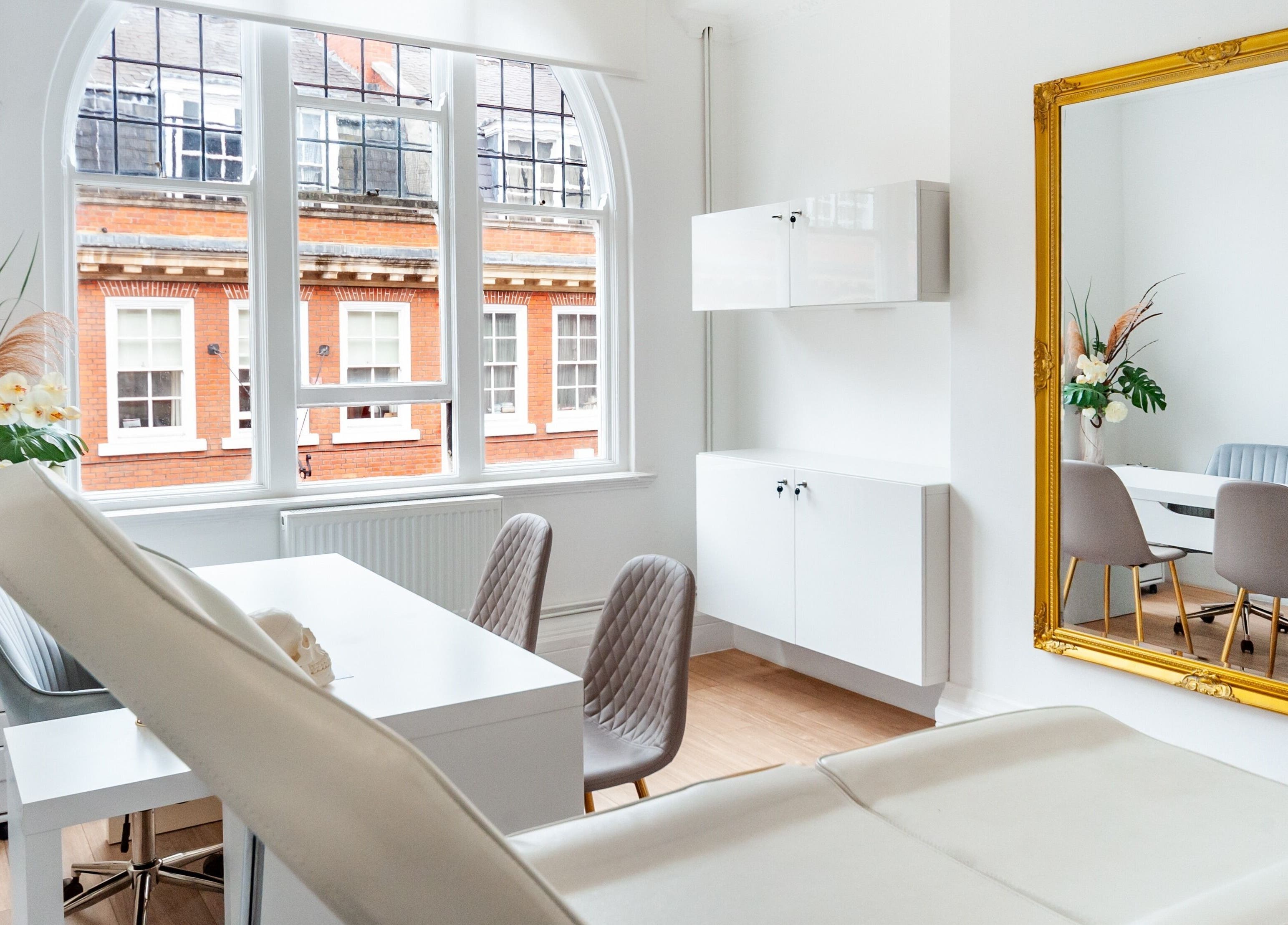 Bright, elegant treatment room at Trikwan Aesthetics, London, England, GB, featuring modern decor and large mirror.