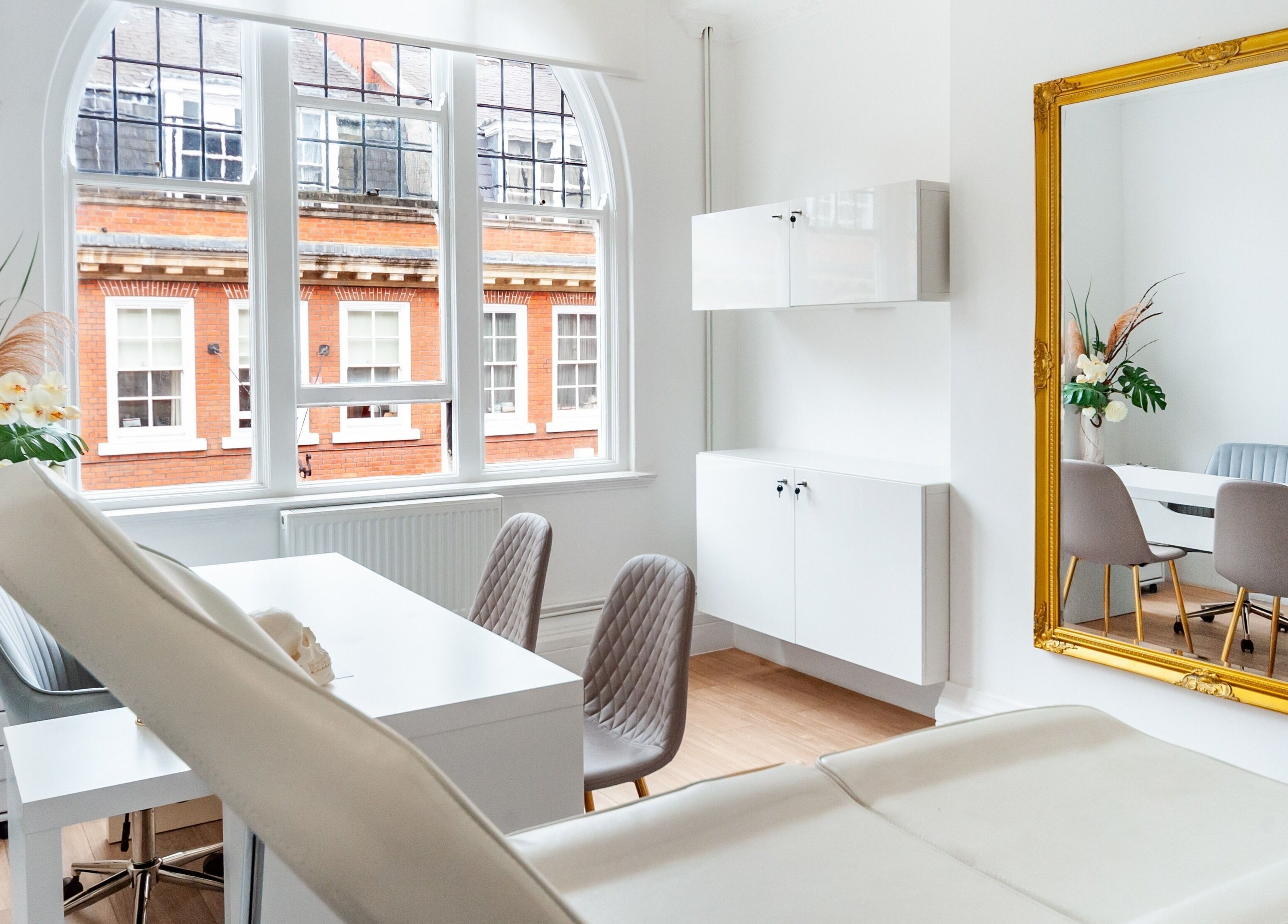 Bright, elegant treatment room at Trikwan Aesthetics, London, England, GB, featuring modern decor and large mirror.