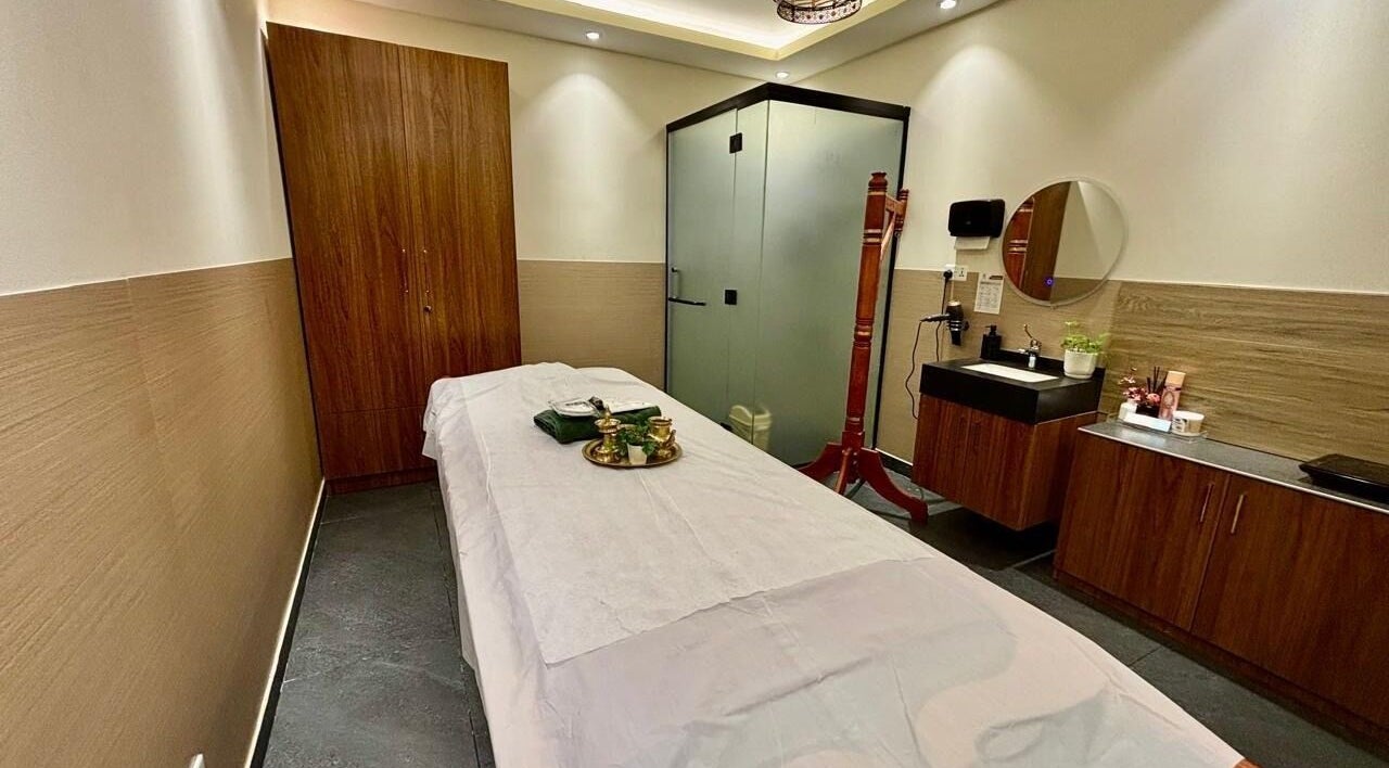 Relaxing treatment room at Ayur Sparsha Ayurveda Centre, Dubai, with massage table and elegant decor.