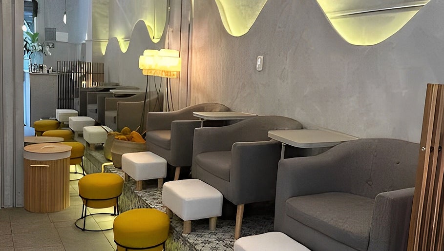 Interior moderno de Calma Nail Bar - Condesa en Ciudad De México, MX, con sillas grises y taburetes amarillos.