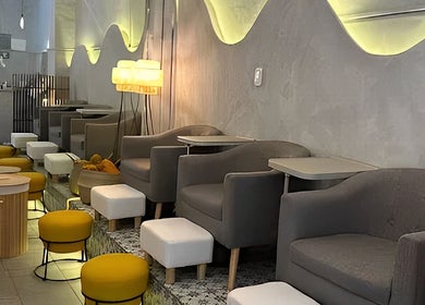 Interior moderno de Calma Nail Bar - Condesa en Ciudad De México, MX, con sillas grises y taburetes amarillos.