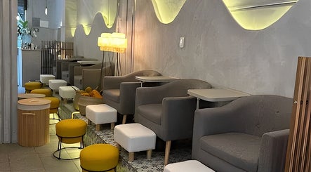 Interior moderno de Calma Nail Bar - Condesa en Ciudad De México, MX, con sillas grises y taburetes amarillos.
