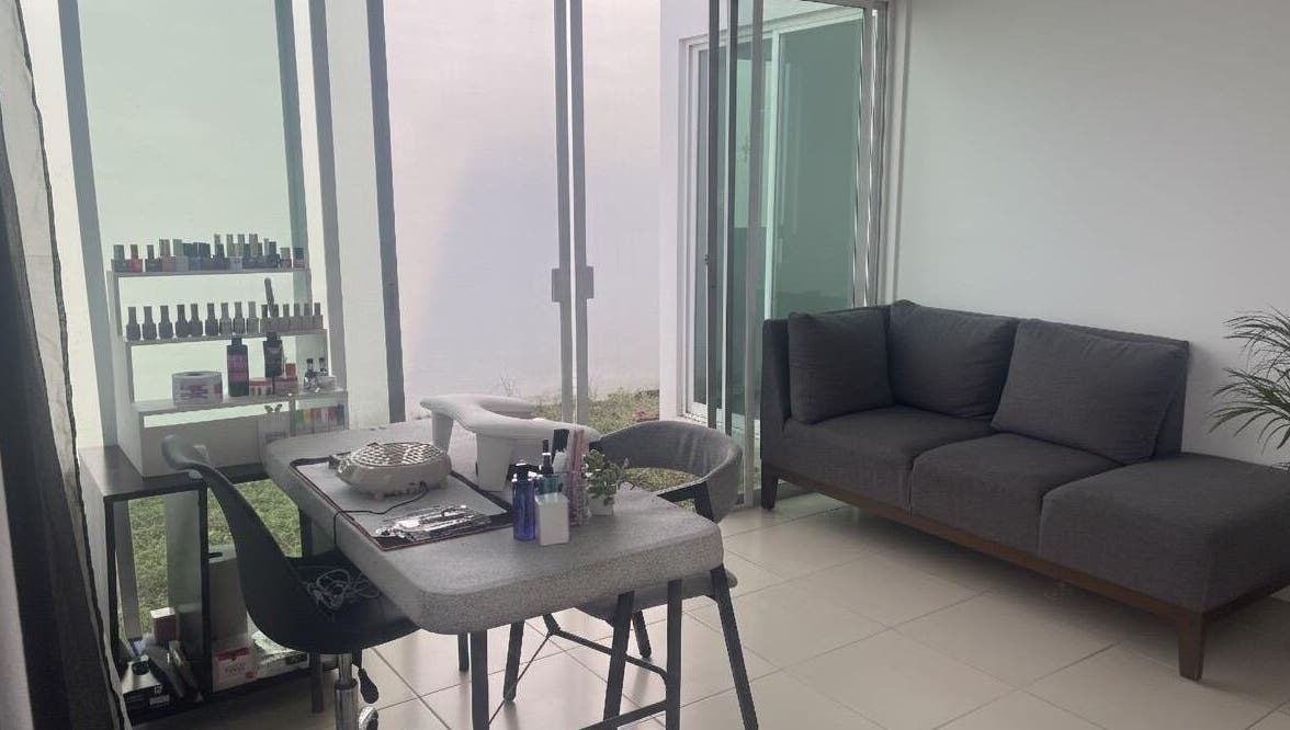 Espacio moderno en Aura Nails, Mérida, Yucatán, MX, con mesa de manicura y sofá gris.