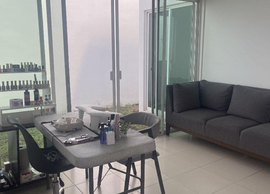 Espacio moderno en Aura Nails, Mérida, Yucatán, MX, con mesa de manicura y sofá gris.