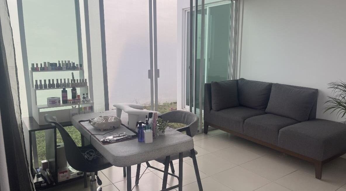 Espacio moderno en Aura Nails, Mérida, Yucatán, MX, con mesa de manicura y sofá gris.