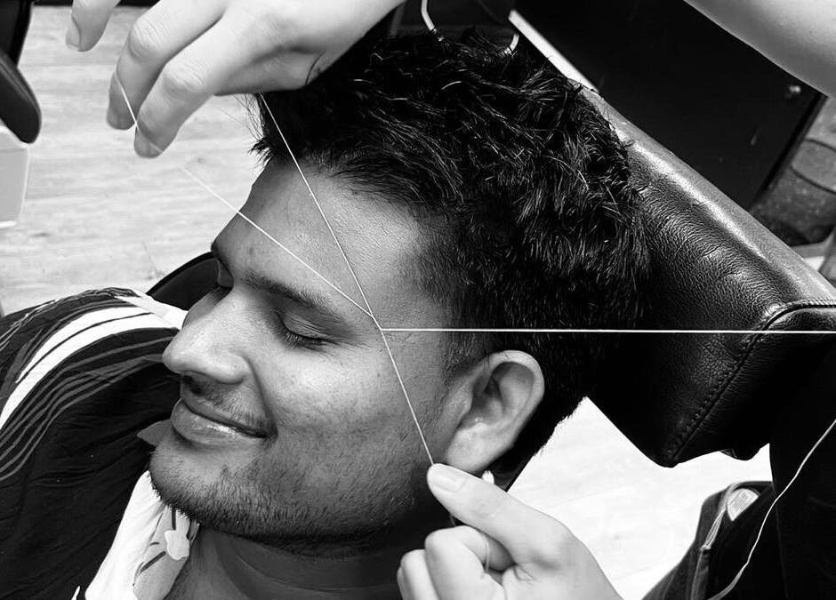Man receiving threading at Paul's Hairdressing for Men in Wallsend, England, GB. A tranquil grooming moment.