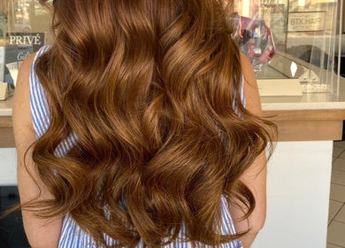 Model with wavy auburn hair at Privé Hairdressing, Naxxar, MT, showcasing vibrant styling.