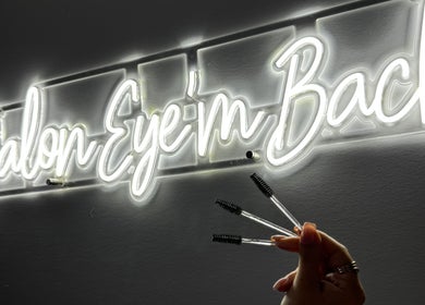 Enseigne néon de Salon Eye’m Back à Laval, Québec, CA, avec brosses à cils en main.
