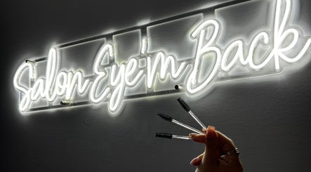 Enseigne néon de Salon Eye’m Back à Laval, Québec, CA, avec brosses à cils en main.