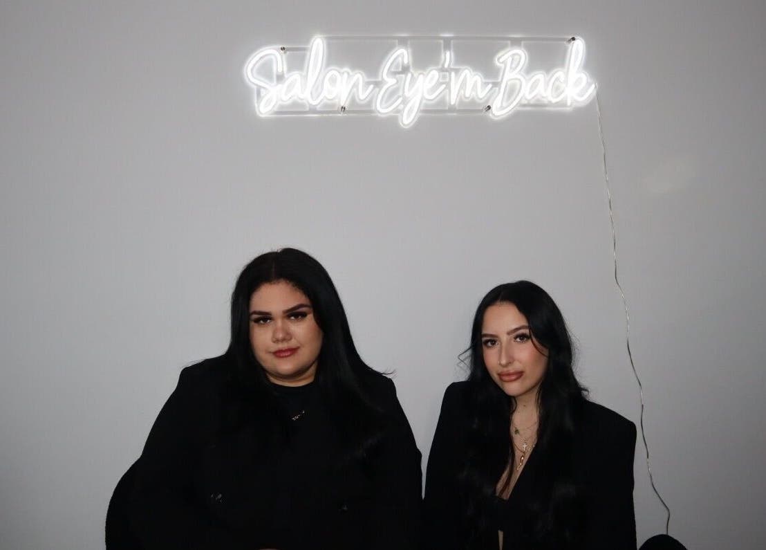 Deux personnes sous l'enseigne Salon Eye’m Back à Laval, Québec, CA.