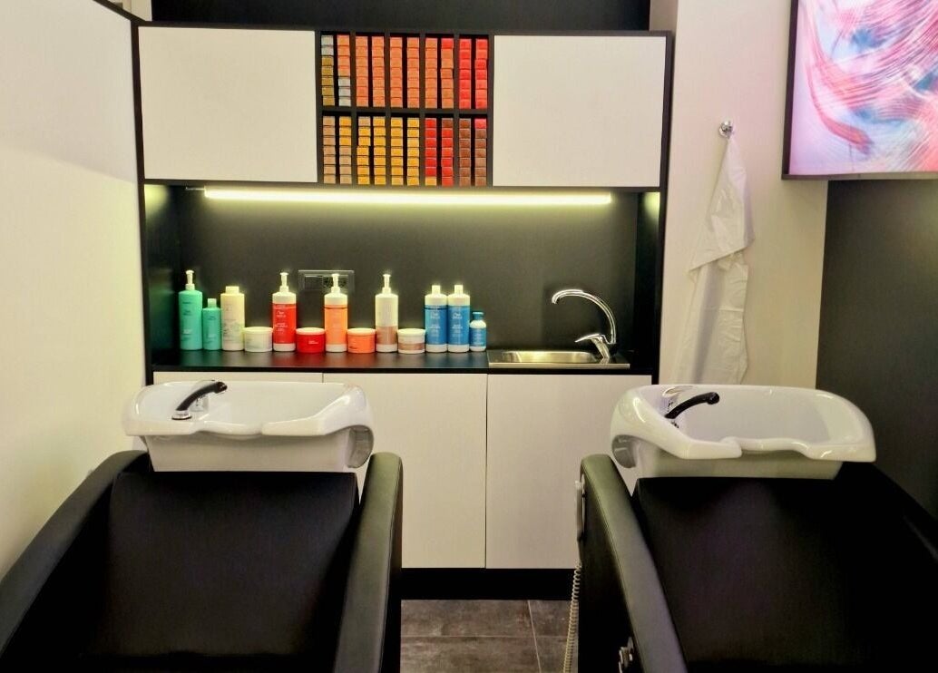 Lavelli moderni in salone HairPro.Tv, Bellizzi, Campania, IT con scaffali di prodotti colorati.