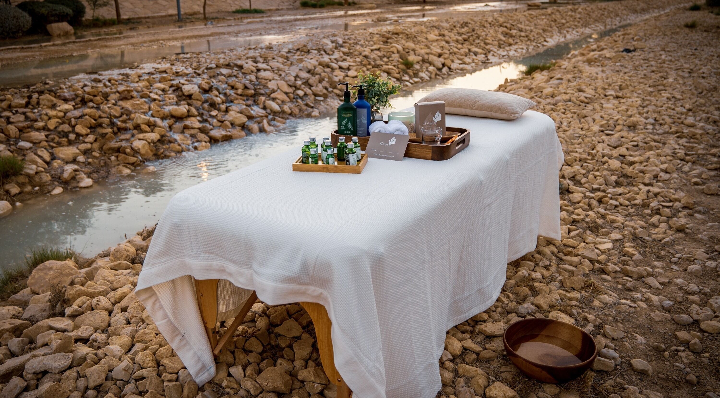 Relaxing outdoor massage setup at Utopia Spa, Riyadh, Riyadh Province, SA, by a tranquil creek.