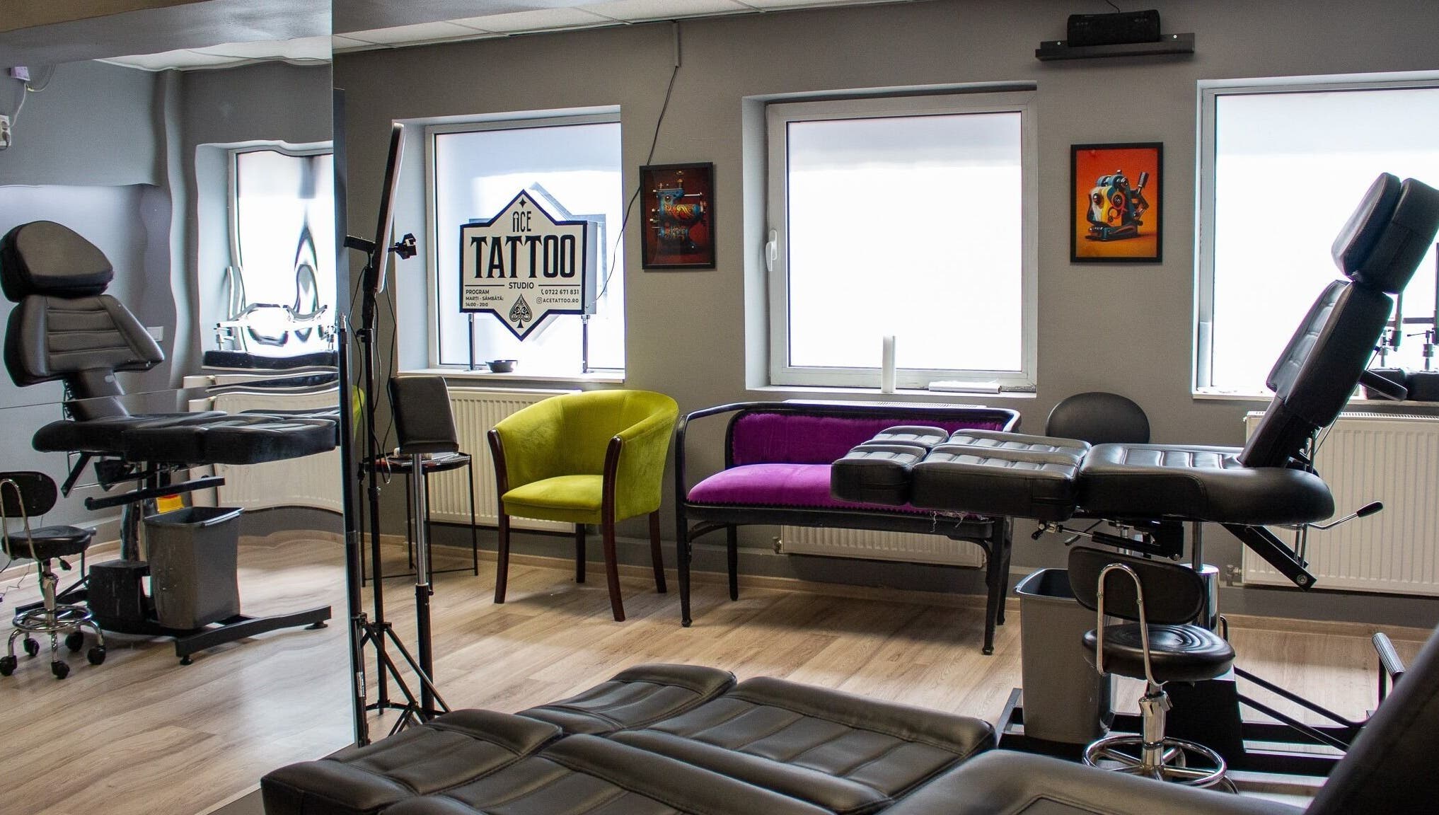Interior modern al Ace Tattoo Parlour din București, București, RO, cu scaune confortabile și artă pe pereți.