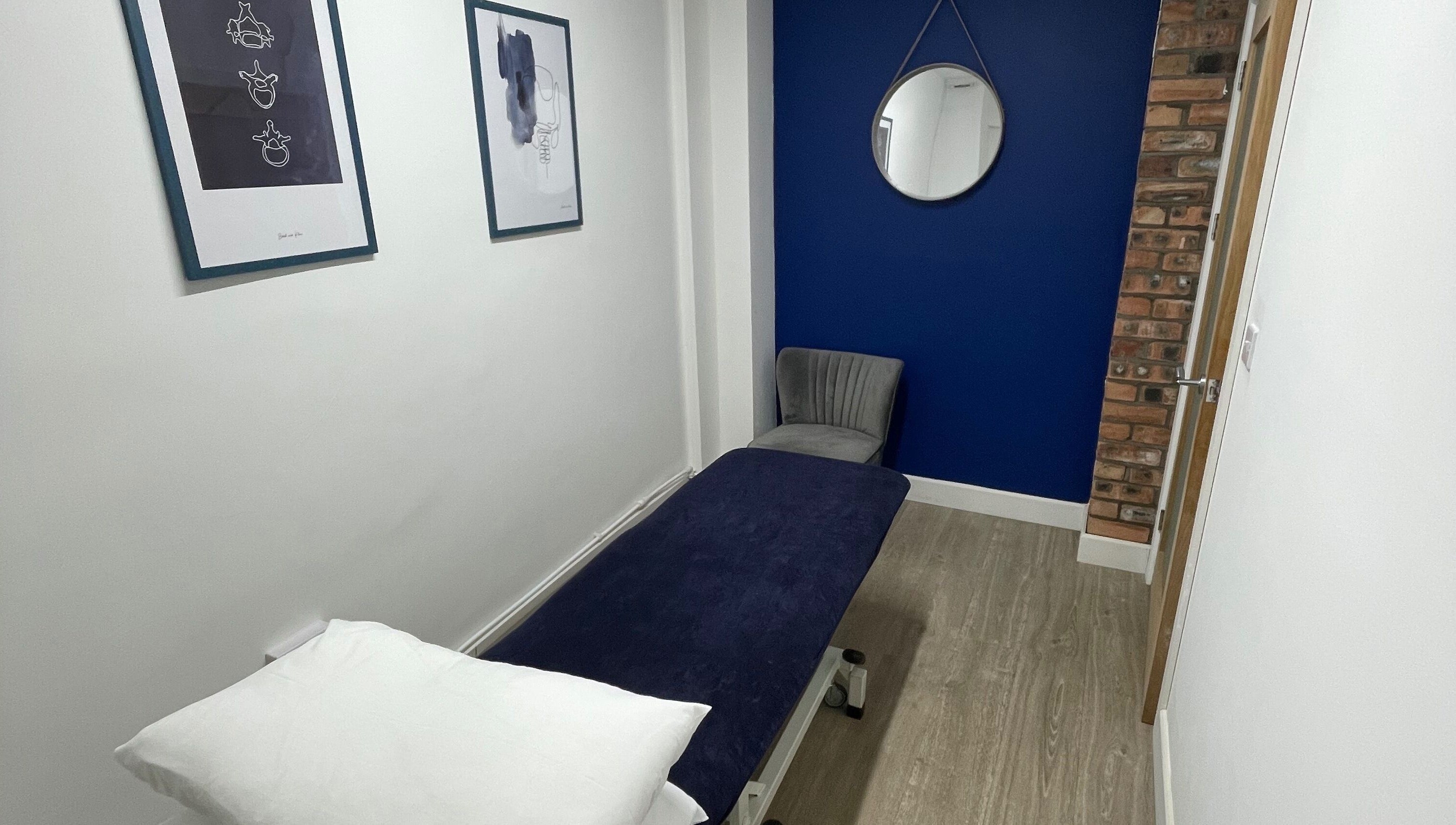Therapy room with deep blue wall and therapy bed at OsteoHub Mumbles, Swansea, Wales, GB.