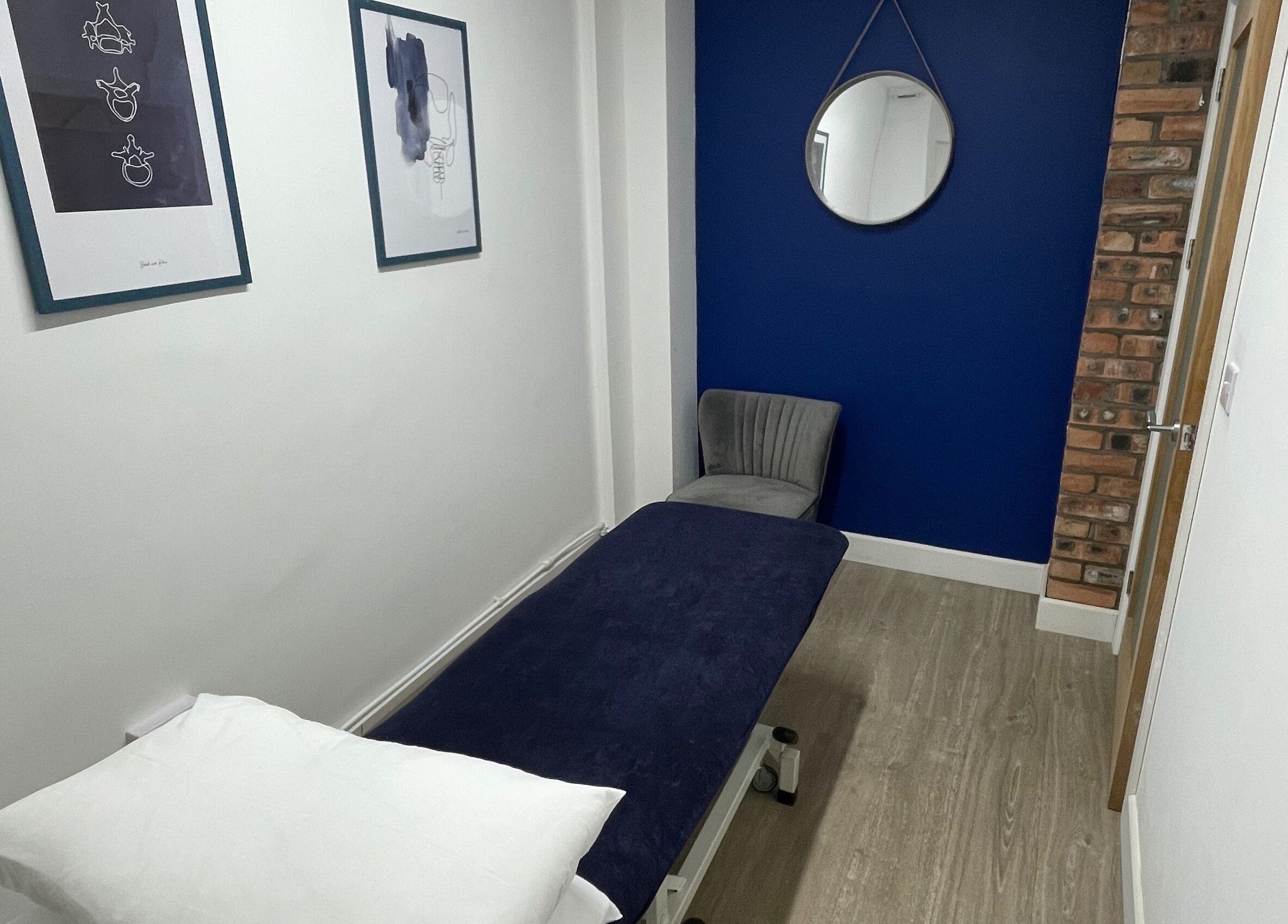 Therapy room with deep blue wall and therapy bed at OsteoHub Mumbles, Swansea, Wales, GB.