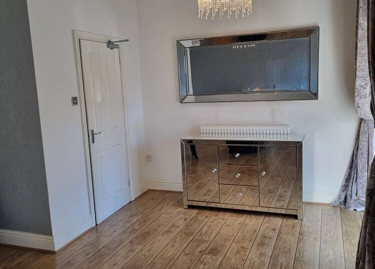 Elegant mirrored dresser and chandelier at Oaktree Parc Clinic, Birchgrove, Wales, GB, enhancing room's ambiance.