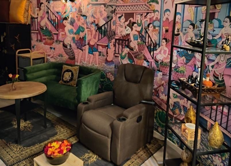 Innenraum von Pimpiman Thai Spa in Bern, Bern, CH mit thailändischen Wandbildern und gemütlichem Sitzbereich.