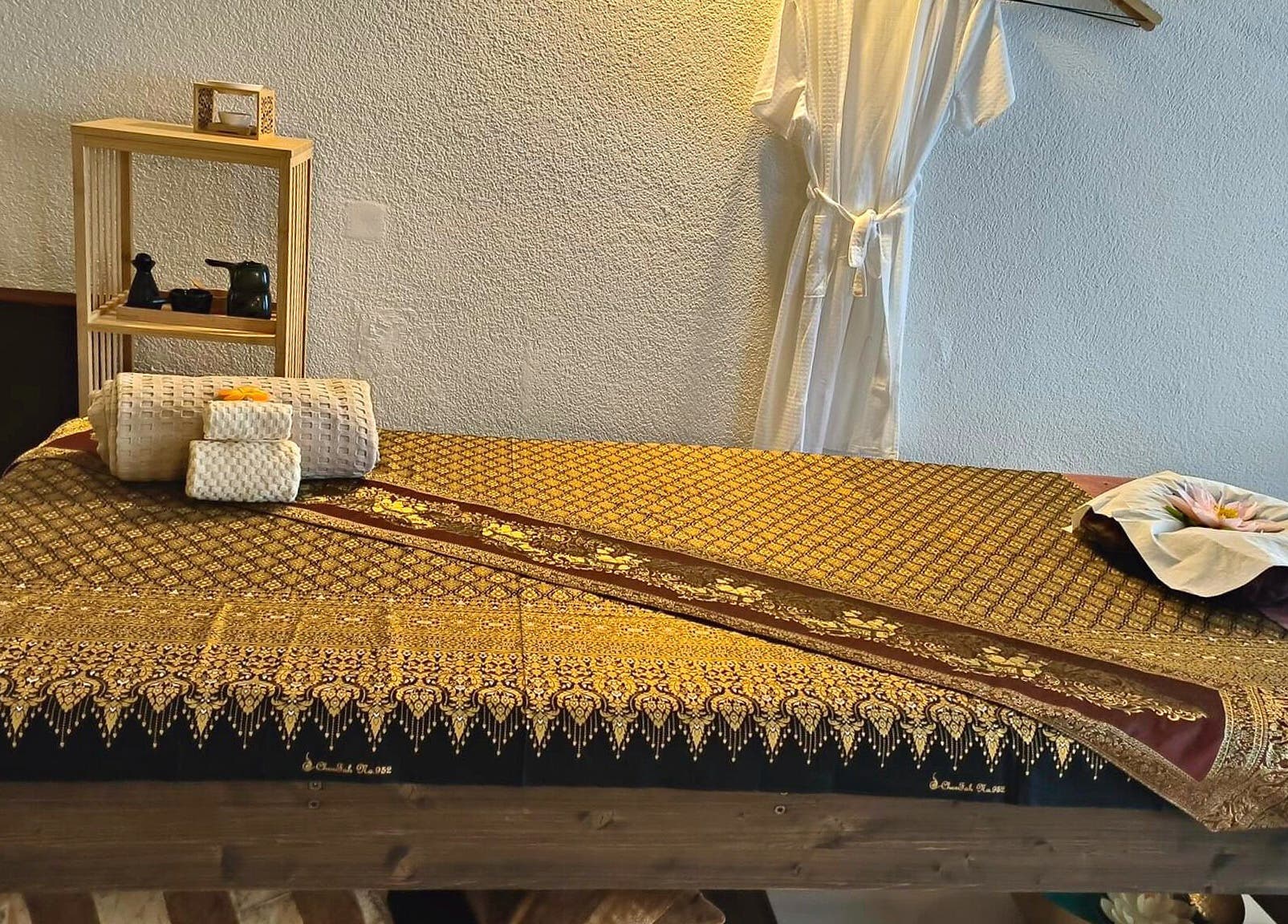 Traditionelle Thai-Massagebank im Pimpiman Thai Spa, Bern, Bern, CH, dekoriert mit goldenen Mustern.