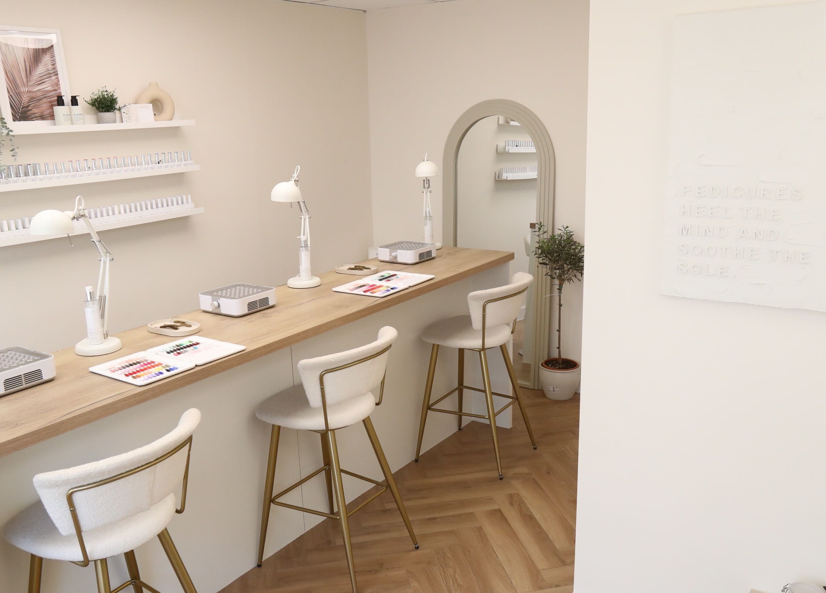 Elegant nail bar with plush chairs at Cure&Co., Chepstow, GB. Displays of nail polish and decor adorn the space.