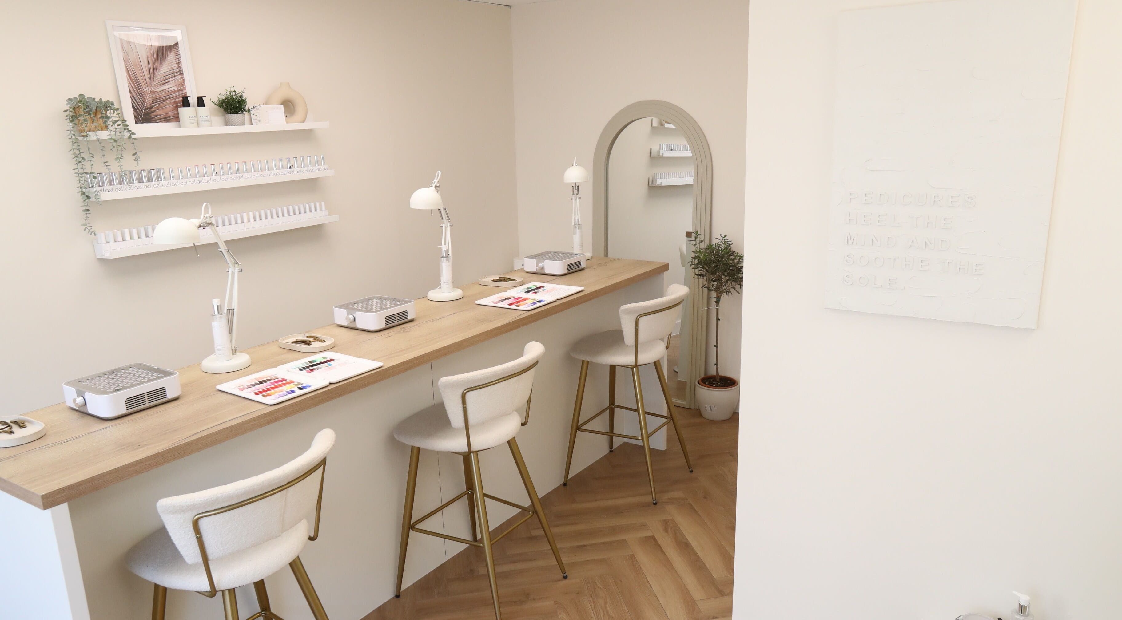 Elegant nail bar with plush chairs at Cure&Co., Chepstow, GB. Displays of nail polish and decor adorn the space.