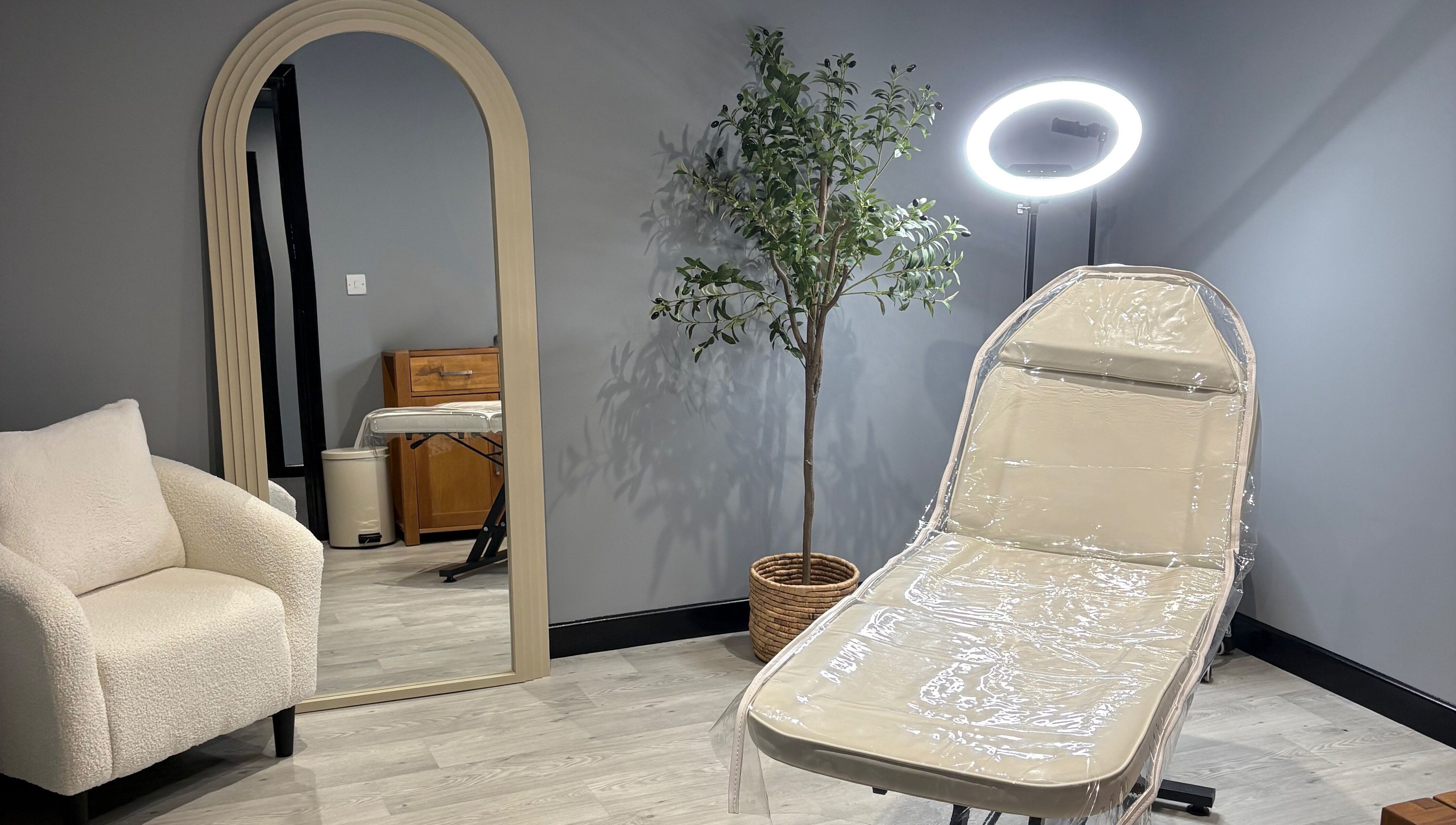 Elegant treatment room at All About Aesthetics, Fareham, England, GB with chair, mirror, and plant.