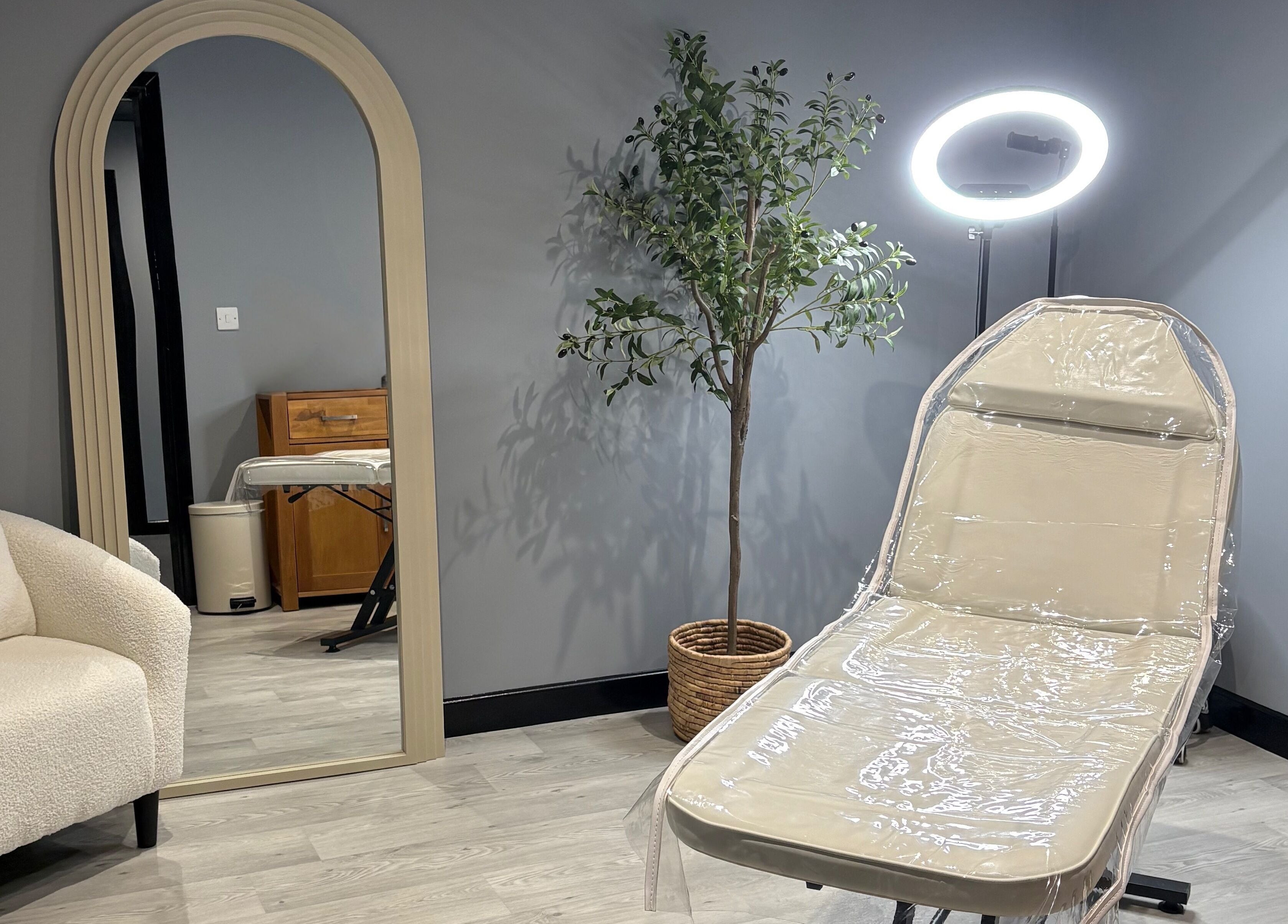 Elegant treatment room at All About Aesthetics, Fareham, England, GB with chair, mirror, and plant.